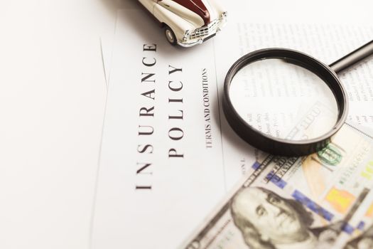 pexels photo 10341357 10341357 Close-up image of an insurance policy with a magnifying glass, money, and toy car.